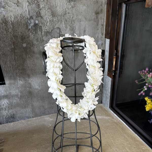 White orchid lei draped over a black metal stand