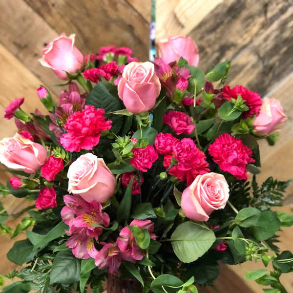 Pink roses and carnations in a tall vase