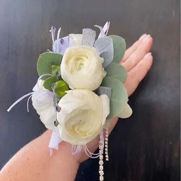 Small wrist corsage with white roses and pale blue accents