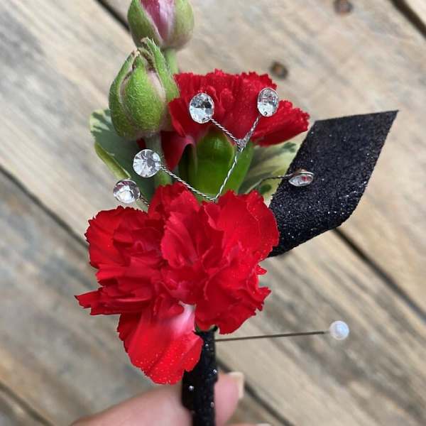 Red carnation boutonniere with rhinestone accents and black ribbon