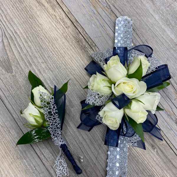 White rose corsage and boutonniere with navy ribbon and silver trim