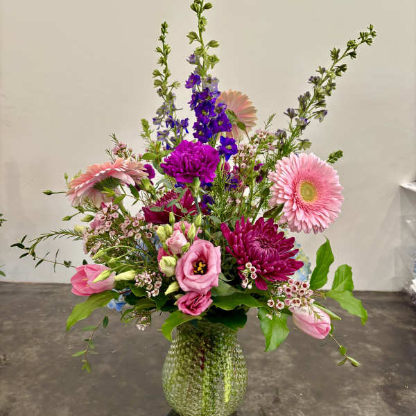 Mixed pink and purple flower arrangement in a textured glass vase