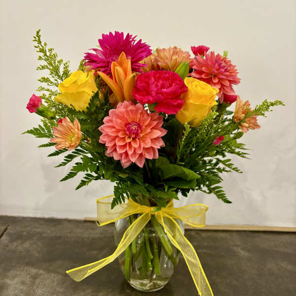Colorful mixed bouquet in a glass vase with a yellow ribbon