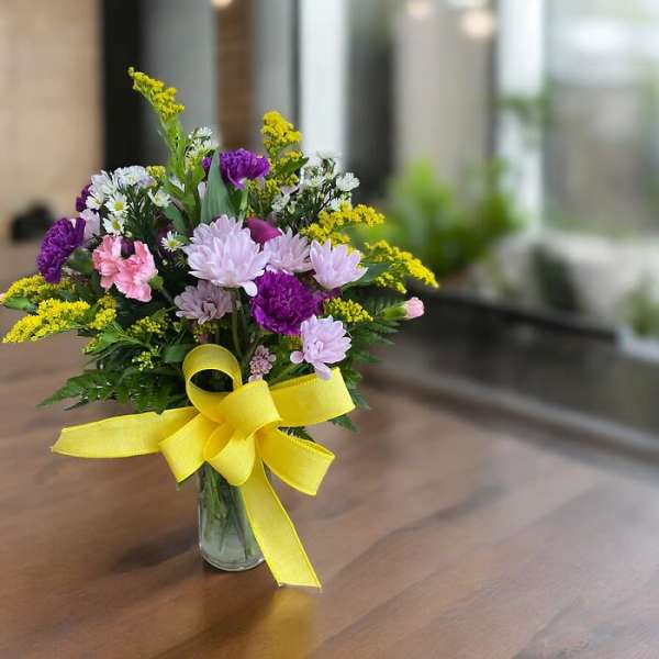 Mixed bouquet in a glass vase with a yellow ribbon