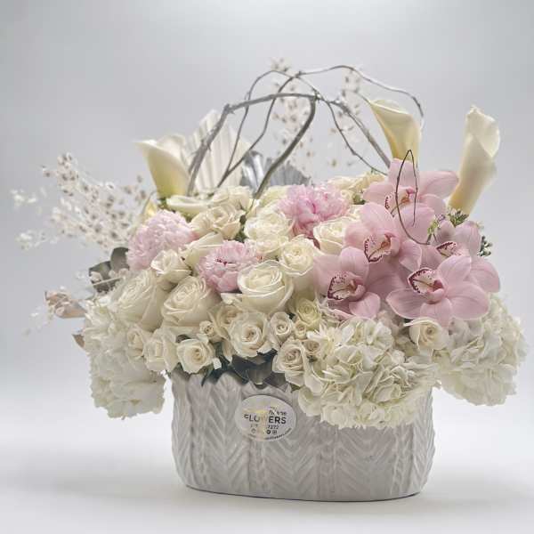 White roses and pink orchids arranged in a textured silver vase