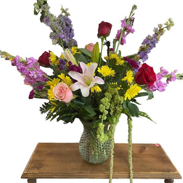 Mixed bouquet with roses, lilies, and yellow daisies in a glass vase
