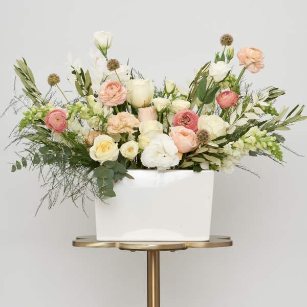 Mixed pastel flowers arranged in a white rectangular vase