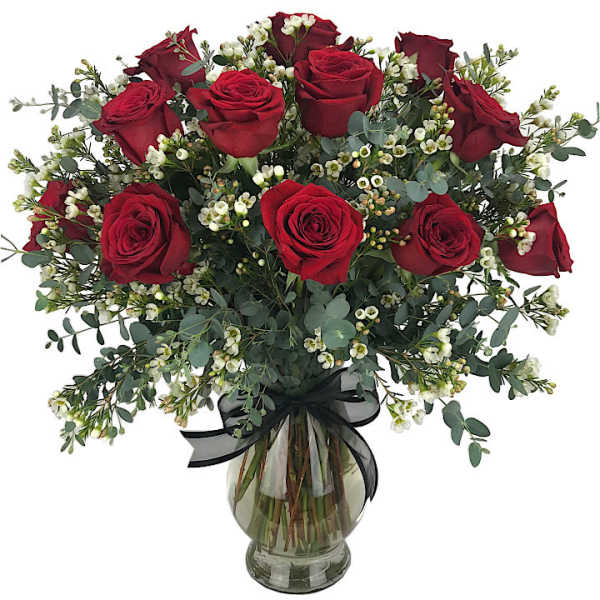 Red roses arranged in a glass vase with white filler flowers