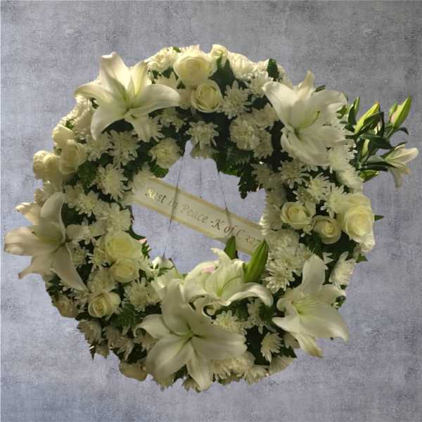 White funeral wreath with lilies and roses on a gray background