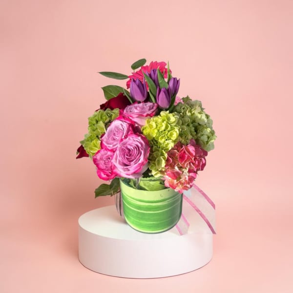 Bouquet of pink roses, purple tulips, and green hydrangeas in a green vase