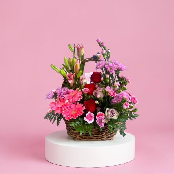 Basket arrangement of pink and red flowers with lilies and roses