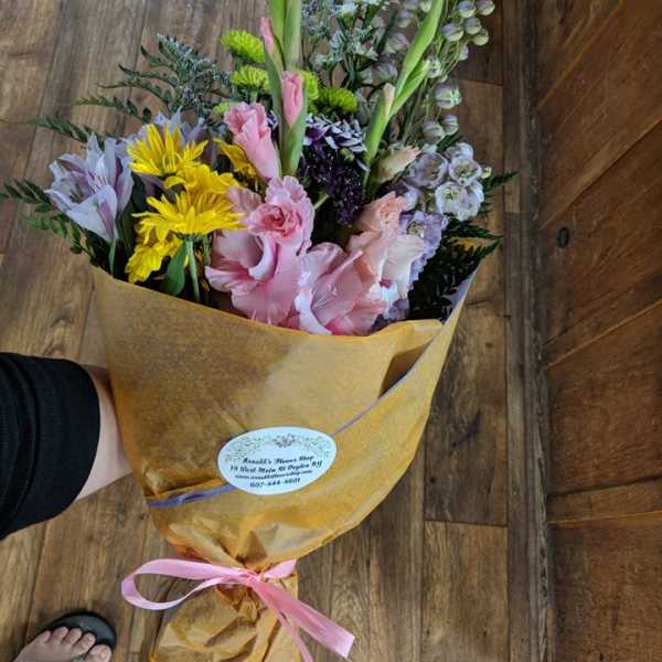 Mixed bouquet of pink, yellow, and lavender flowers wrapped in gold paper