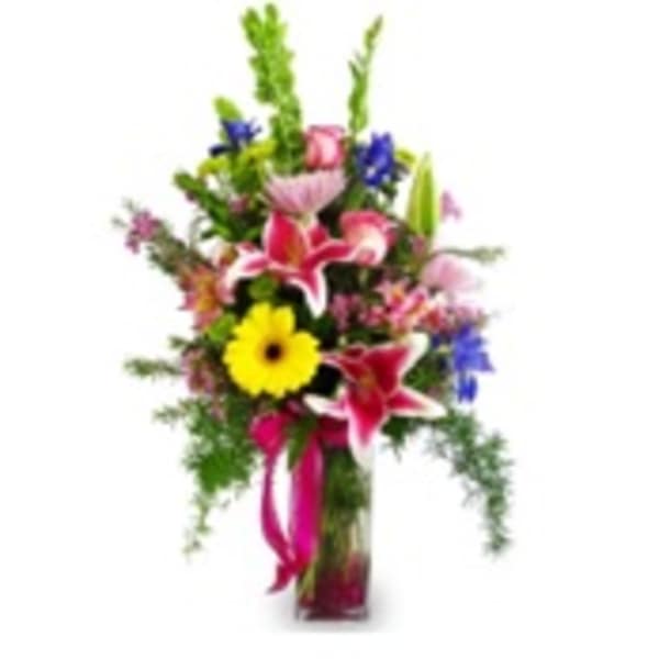 Tall mixed flower arrangement in a glass vase with bright pink and yellow blooms