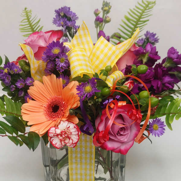 Mixed bouquet in a clear glass vase with pink, purple, and peach flowers
