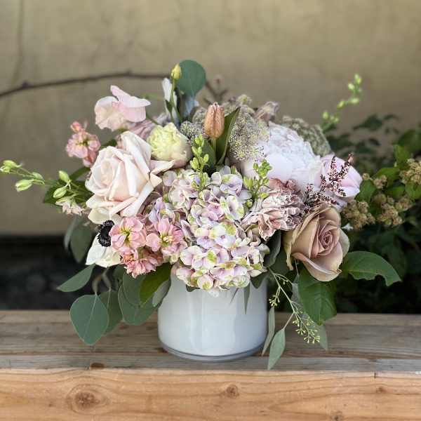 Pastel flower arrangement in a white vase with roses and hydrangeas