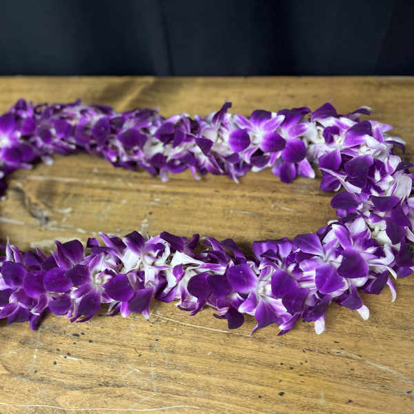 Purple and white orchid lei on a wooden table