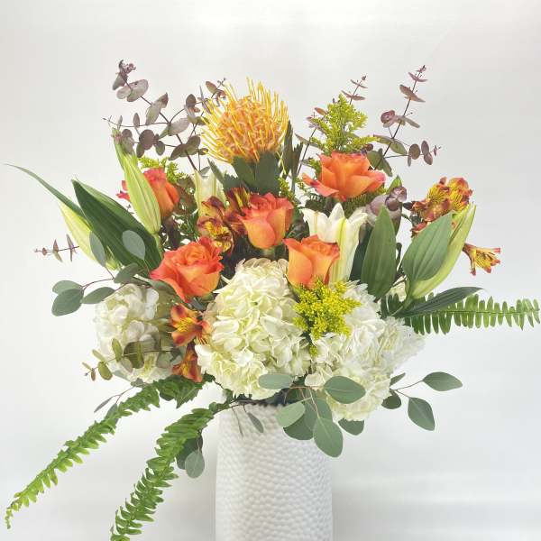 Orange and white floral arrangement in a white vase