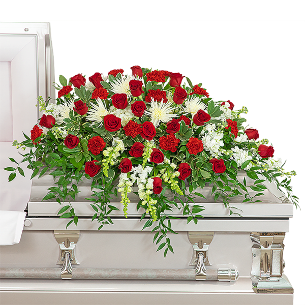 Red roses and white flowers arranged on a white casket