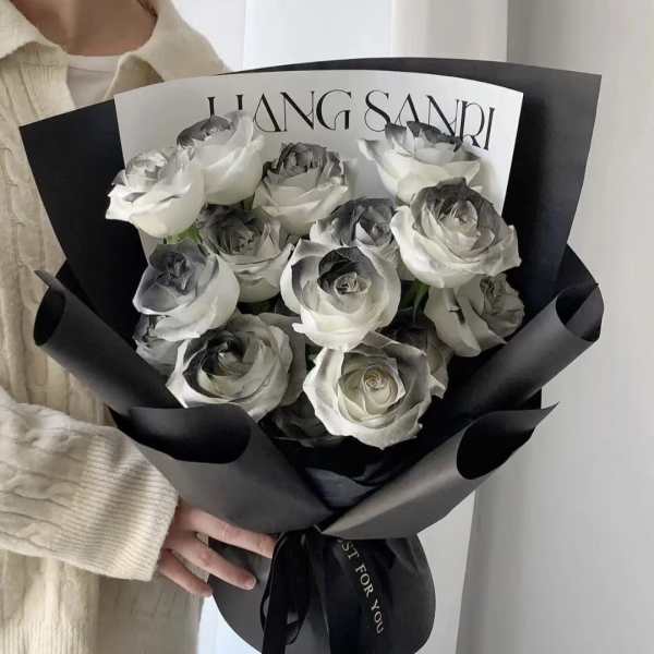 Bouquet of white roses wrapped in black paper
