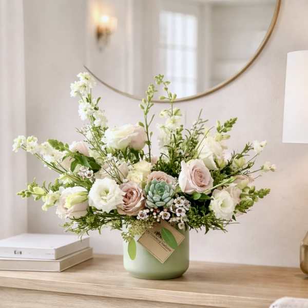 Pastel bouquet of roses and white blooms in a green vase
