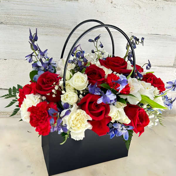 Basket arrangement of red and white roses with blue flowers