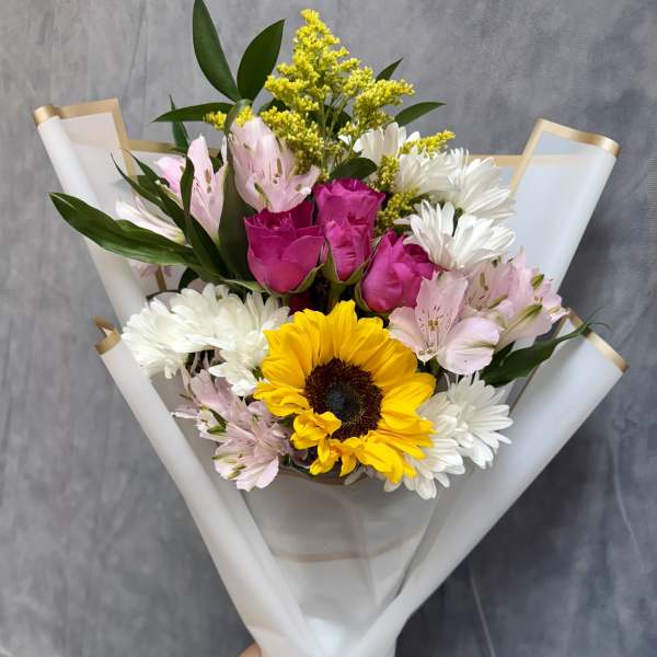 Hand-tied bouquet with sunflowers, pink roses, white daisies, and alstroemeria