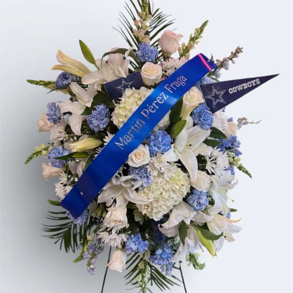 Standing floral spray with white lilies and blue flowers on an easel