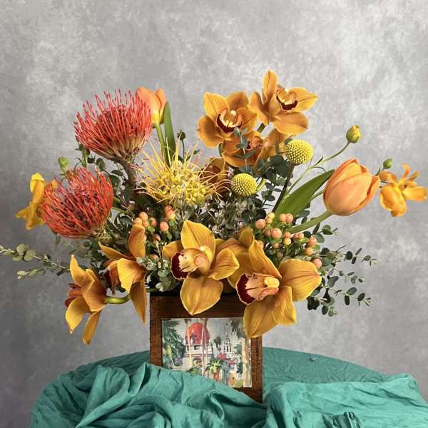 Orange and yellow floral arrangement in a wooden frame container