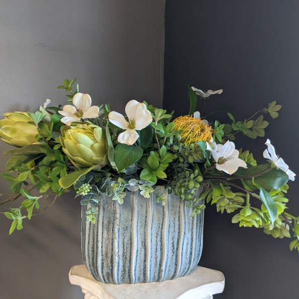 Arrangement of white flowers and green succulents in a striped ceramic pot