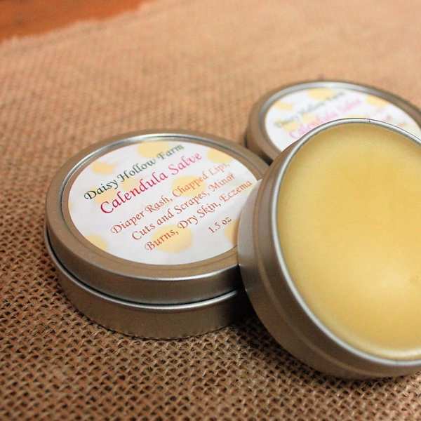 Three tins of calendula salve on burlap fabric