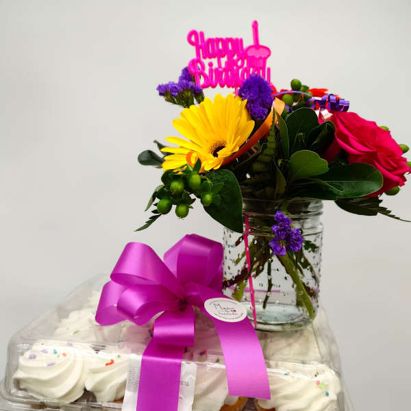 Birthday flower arrangement with cupcakes and a pink topper in a jar vase