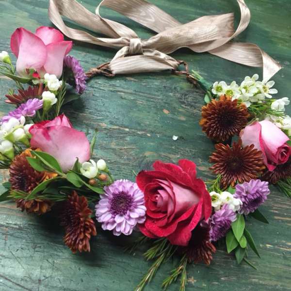 Floral wreath with pink roses and purple daisies on a ribbon tie