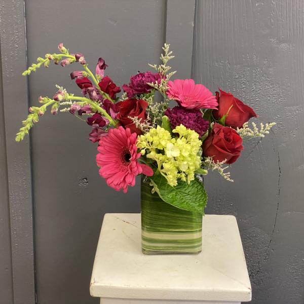 Mixed bouquet of red and pink flowers in a glass vase