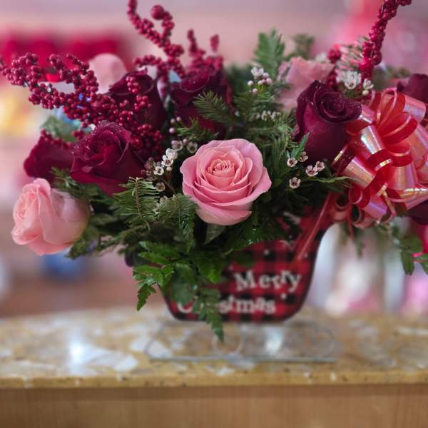 Pink and burgundy roses in a glass vase with a red ribbon bow