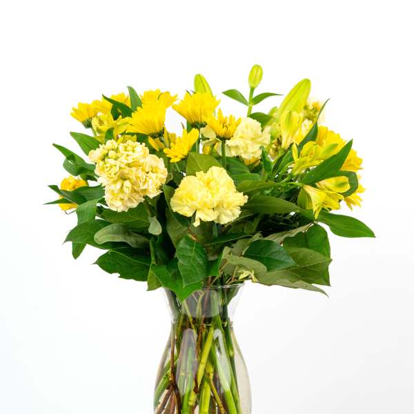 Yellow carnations, chrysanthemums, and lilies arranged in a clear glass vase