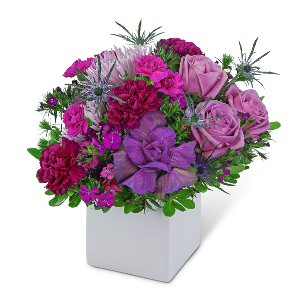 Purple and pink floral arrangement in a white square vase