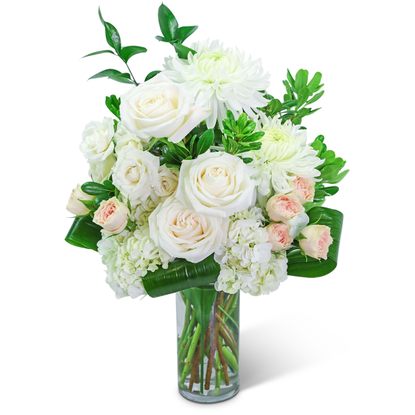 White roses and chrysanthemums in a clear glass vase with green foliage