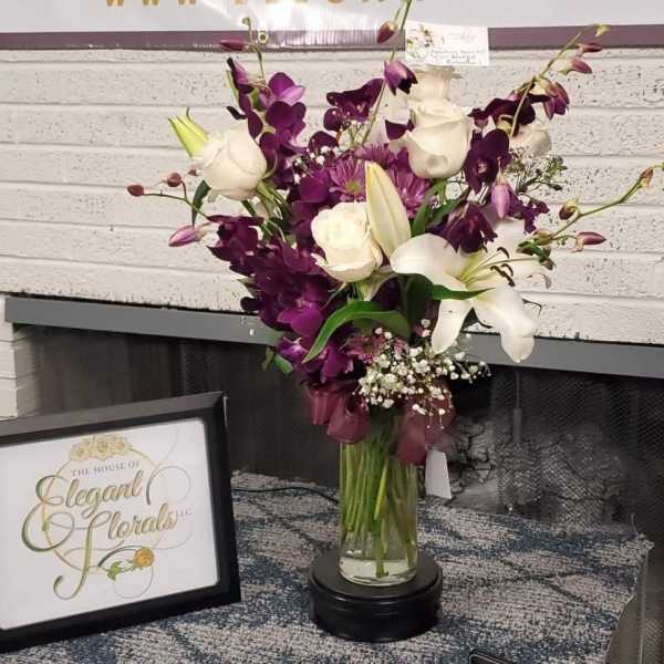 Purple and white floral arrangement in a glass vase