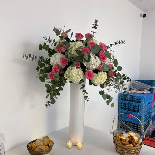 Tall floral arrangement of pink roses and white hydrangeas in a white vase
