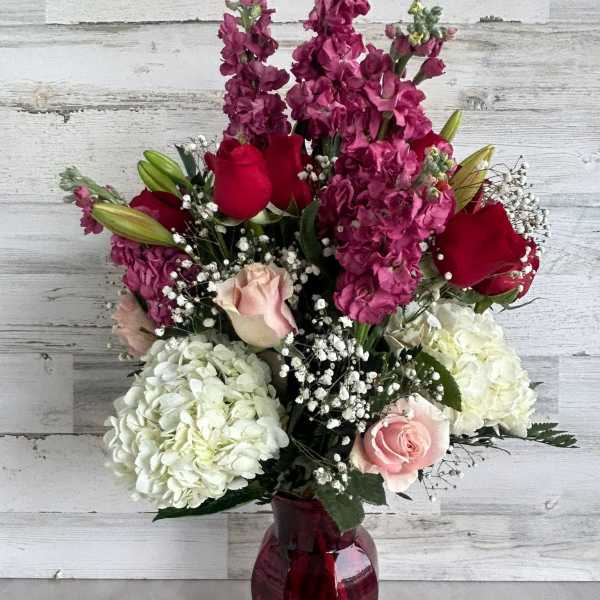 Bouquet of red and pink roses with white hydrangeas in a burgundy vase