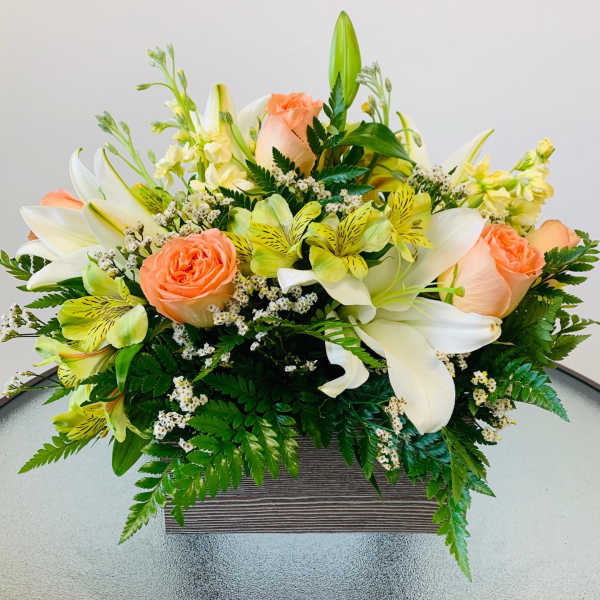 Peach roses and white lilies in a low rectangular container