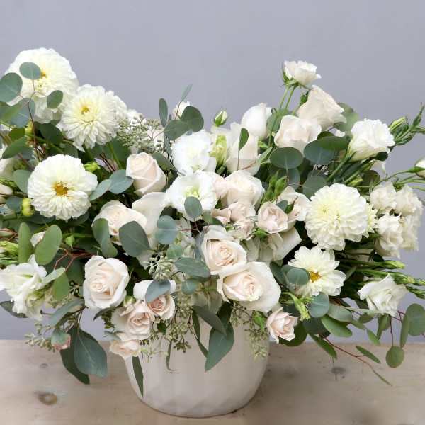 Large white and cream flower arrangement in a white ceramic vase