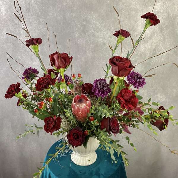 Red roses and purple flowers in a white vase