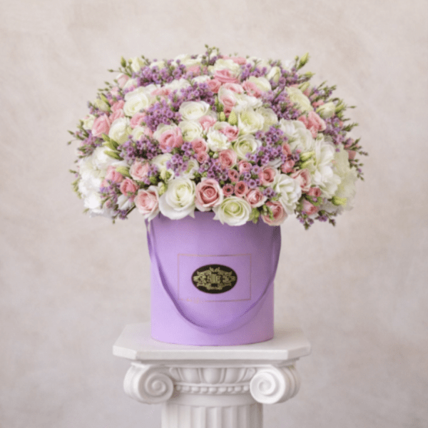 Pink and white roses with purple filler in a lavender hatbox