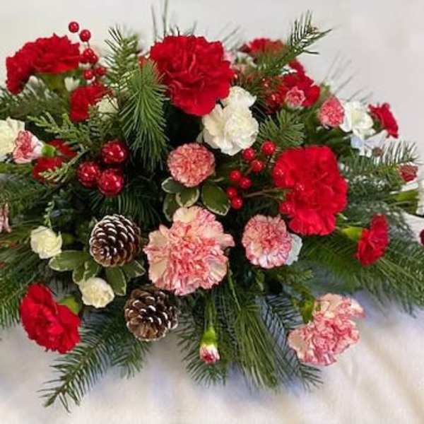 Red and pink carnations with pinecones in a holiday arrangement