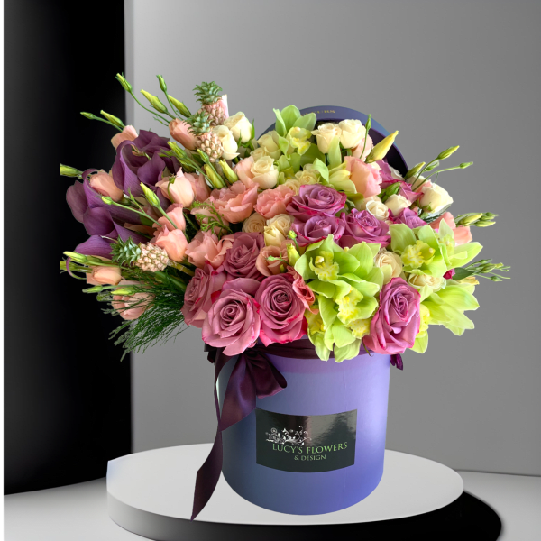 Mixed bouquet of pink, purple, and green flowers in a lavender hat box