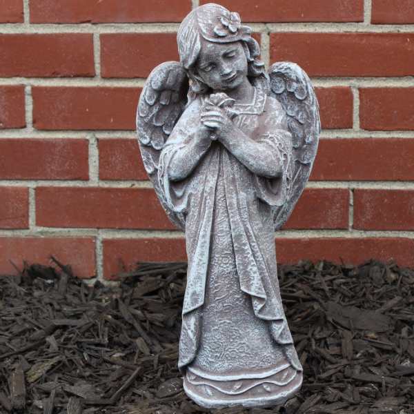 Small angel statue standing against a brick wall