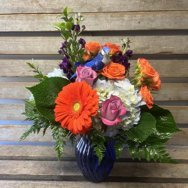 Colorful mixed bouquet in a blue vase with roses, hydrangea, and a gerbera daisy