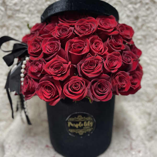 Bouquet of red roses in a black hat box with ribbon