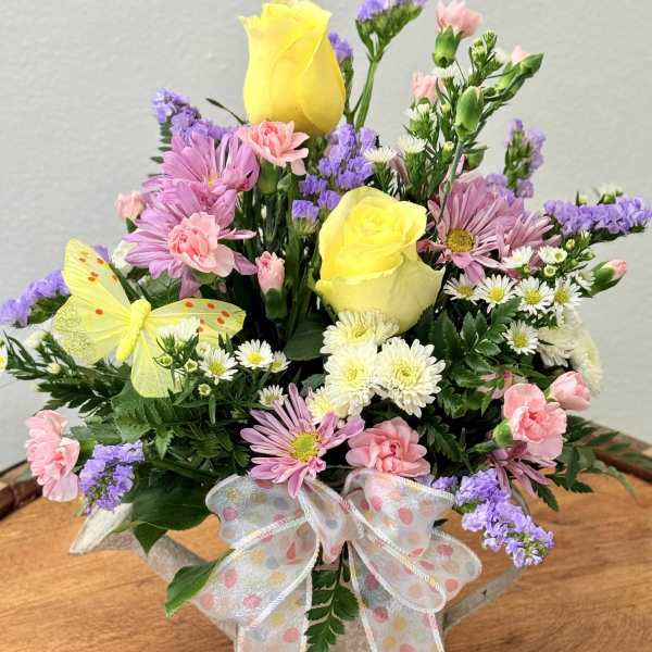 Mixed bouquet with yellow roses, pink daisies, and a polka-dot ribbon in a basket